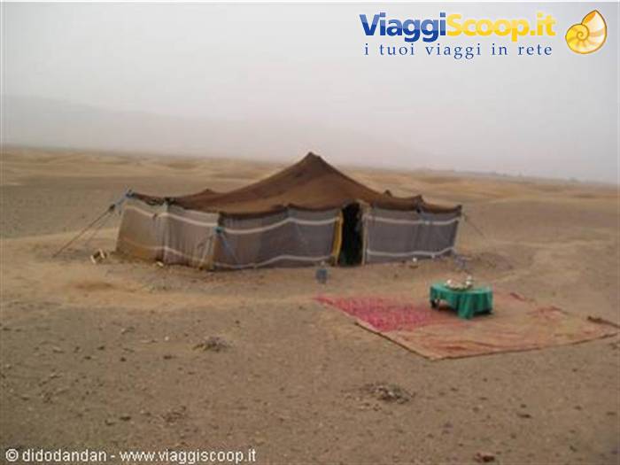 Berber tent in the desert with carpet and small table outside, hazy sky