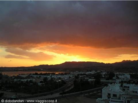 Orange sky and dark clouds over the bay and mountains of Sharm el-Sheikh