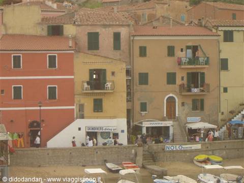 Colorful houses above the harbor, small boats and GIGLIO sign
