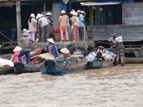 Floating market: boats loaded with fruit and conical-hat vendors on muddy river