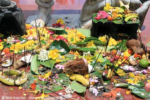 Flower offerings, bananas and burning incense sticks on a red temple floor