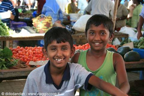 Two smiling boys in front of tomato stalls at the market