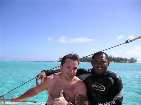 Tourist and diving instructor in wetsuit on boat, turquoise water and island