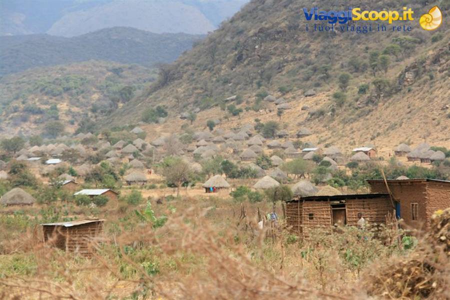 Village with thatched huts and brick houses at the foot of the hill