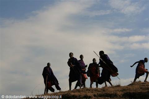 Maasai warriors silhouetted on a hill, red shukas and sticks