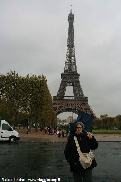 Tourist with umbrella under the Eiffel Tower on a gray rainy day