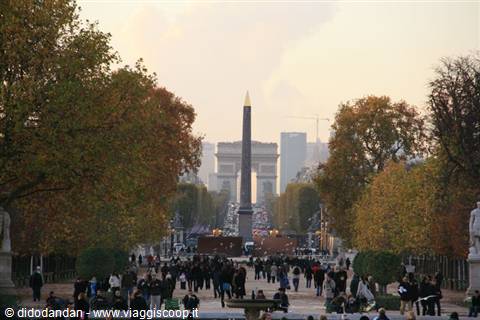 Visitors stroll through the Tuileries Garden toward the Luxor Obelisk and Arc de Triomphe