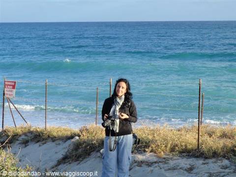 Woman with camera on sandy dunes by turquoise sea in Cabo Pulmo