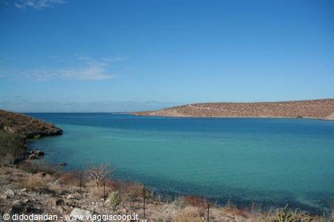 Turquoise bay framed by arid rocky hills under clear sky