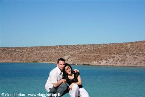Couple hugging in front of sandy beach and turquoise water at Balandra