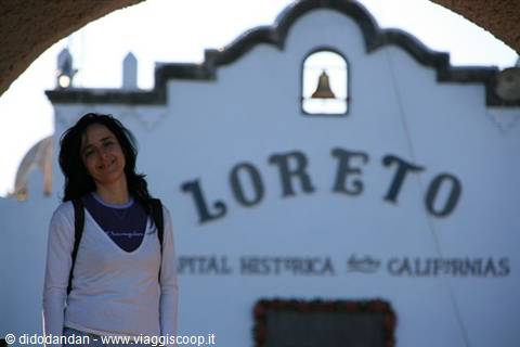 Smiling woman in front of the historic mission sign in Loreto