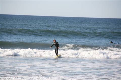 Surfer in black wetsuit on yellow board riding a wave