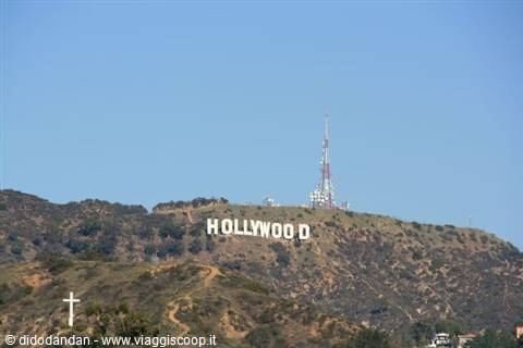 White Hollywood sign on dry hillside, radio antenna, blue sky