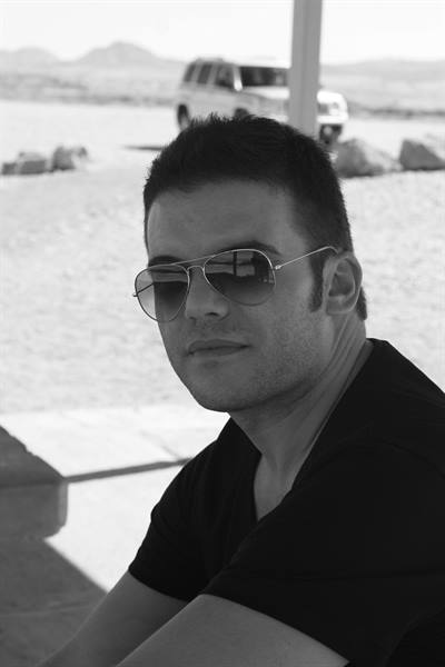 Black and white portrait of a man in sunglasses, jeep behind in the desert
