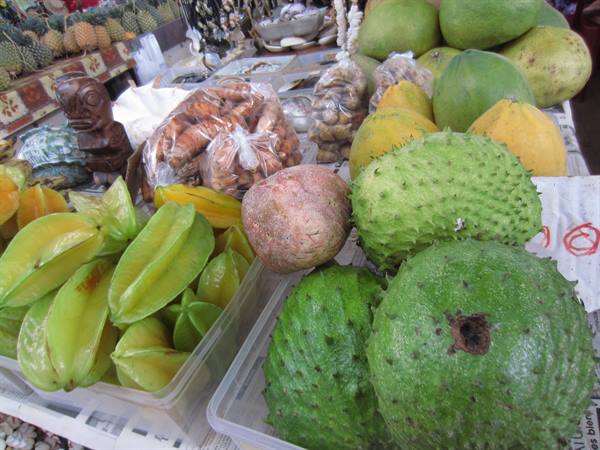 Fruit stall with starfruit and green soursop beside a wooden tiki statue