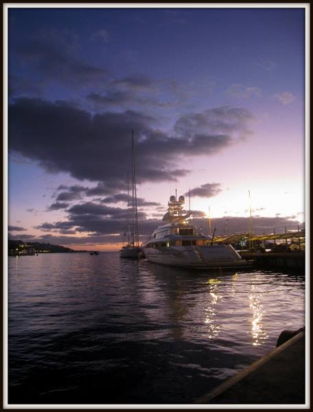Lit yacht moored at the harbor under purple evening sky, water reflections