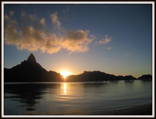 Mount Otemanu in Bora Bora silhouetted over the sea, overwater bungalows