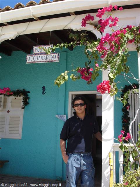 Man in sunglasses at Posada Acquamarina entrance, turquoise walls and bougainvillea