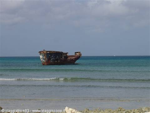 Rusted shipwreck stranded in turquoise waters off the sandy beach