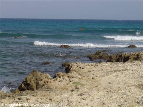 Blue waves breaking on rocks and pale sand