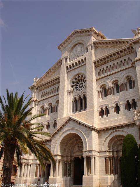 Monaco Cathedral in white stone with rose window, palm tree at left