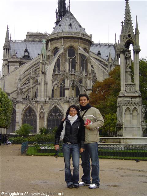 Smiling couple in front of Notre-Dame's Gothic apse in Paris, flying buttresses and spires