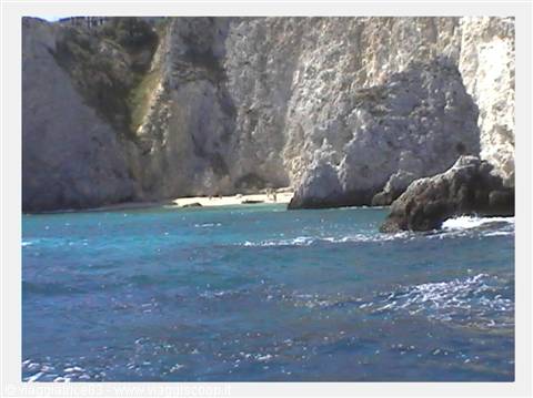 White limestone cliffs over turquoise water, small sandy beach between rocks