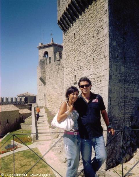 Couple with white bag beside crenellated Guaita tower in San Marino