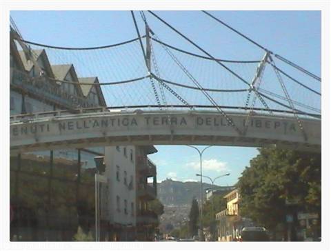 Steel pedestrian bridge with inscriptions, cable arches above the city street