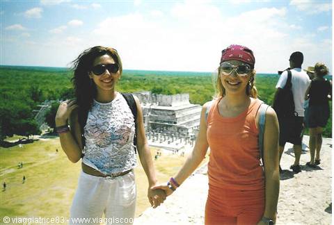 Two tourists holding hands atop a Maya temple above the jungle