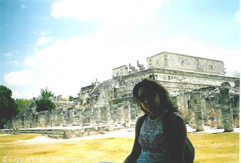 Woman with backpack in front of Chichén Itzá Maya ruins under the sun