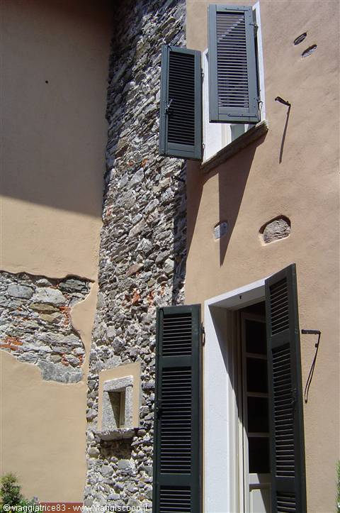 Pink facade with exposed stone wall and open green shutters
