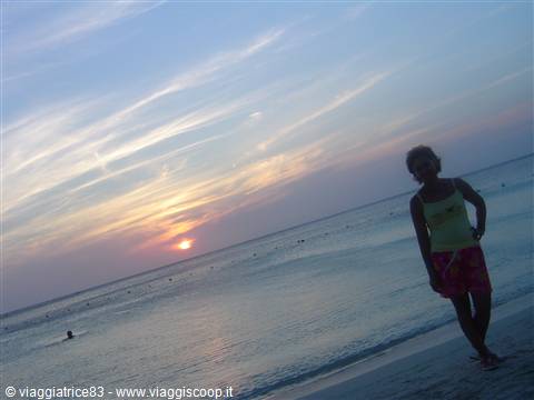 Woman in yellow top and pink shorts on the beach at sunset