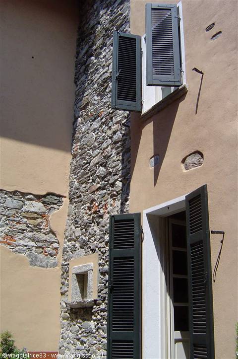 Pink facade with exposed stone wall and open green shutters