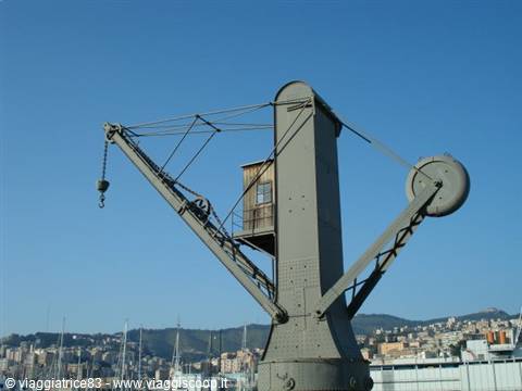 Old iron crane at Genoa port, blue sky and hills behind
