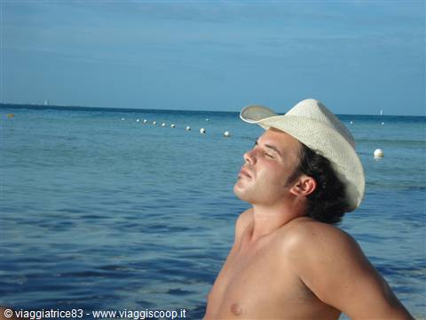 Young man in straw hat by the sea, eyes closed in the sun