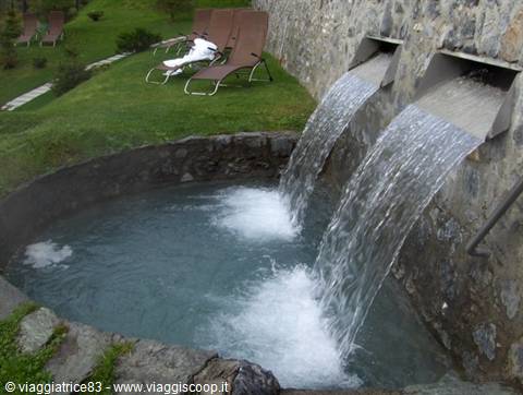 Two thermal water streams pour from stone spouts into a round pool