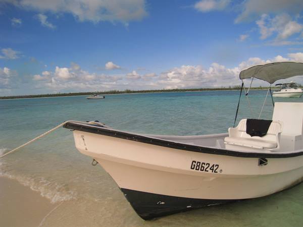 White boat with canopy moored on sandy beach, turquoise water