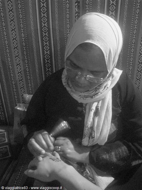 Henna tattoo artist decorating a client's hand