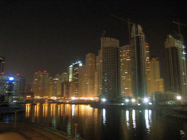 Illuminated Dubai Marina skyscrapers at night reflected in the harbour water