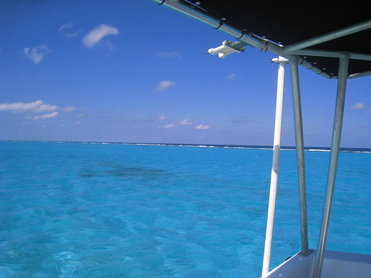 Metal boat near the reef, turquoise water under blue sky