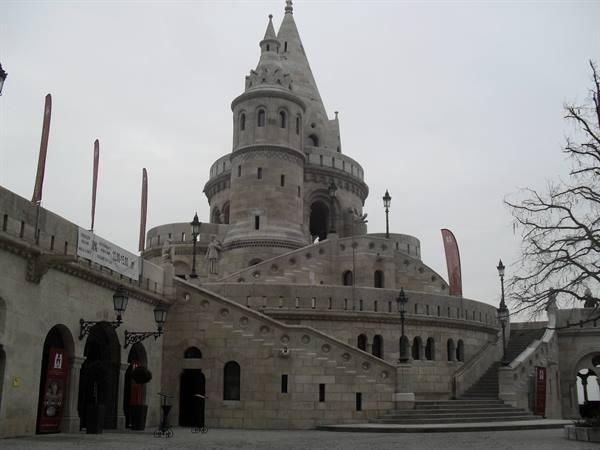 Neo-Gothic stone tower with stairs and terraces under a heavy grey sky
