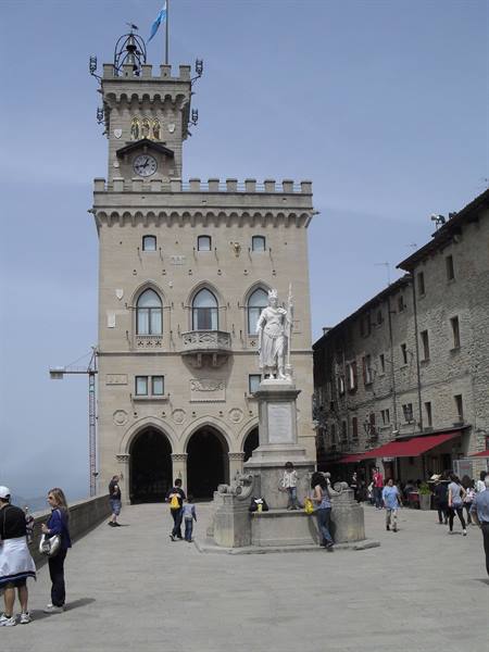 Marble statue in front of San Marino's Palazzo Pubblico, tourists in the square