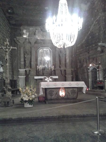 Salt-carved chapel with sculpted altar and crystal chandelier, warm light