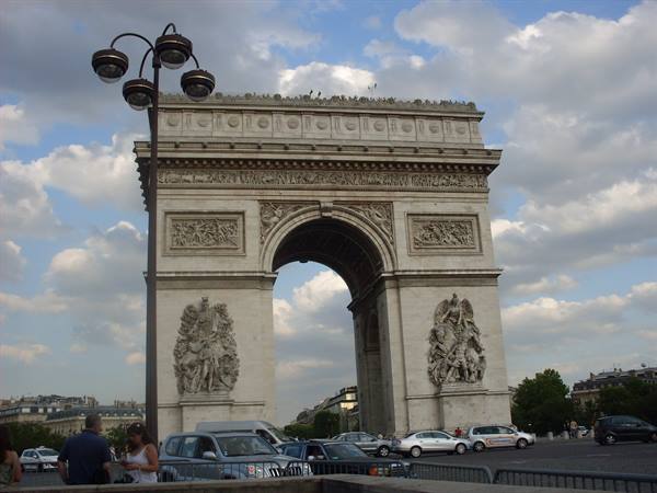 The Arc de Triomphe in Paris under cloudy sky with city traffic