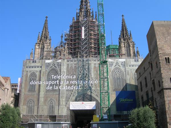 Barcelona Cathedral under restoration, scaffolding on gothic spires against blue sky