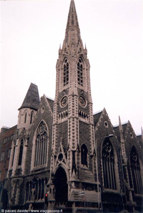 Gothic stone church with clock spire, Dublin, under overcast sky