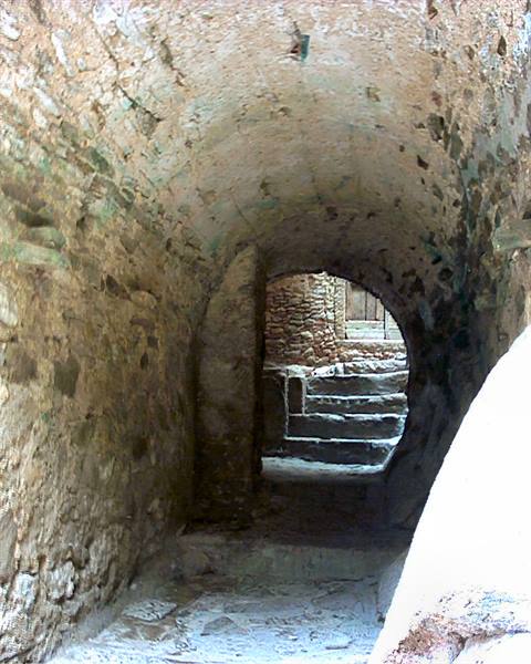 Stone vaulted passage with arch opening onto rock steps