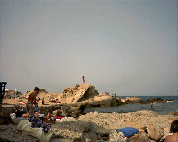 Bathers on limestone rocks, a boy jumping, clear sky over the sea