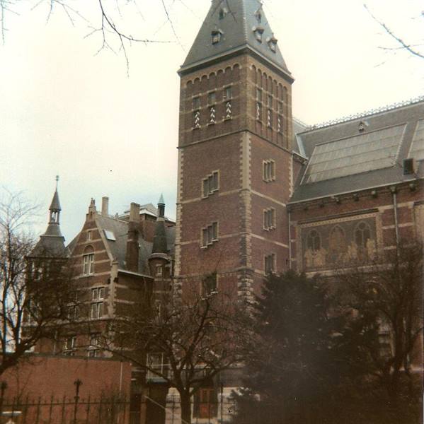 Brick tower of the Rijksmuseum among bare trees, grey sky